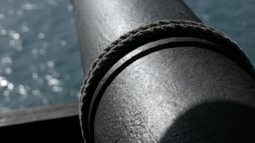 close up pirate cannon under the deck of an 18th century sailing ship with the hatch open facing the sea. Naval pirates warfare equipment