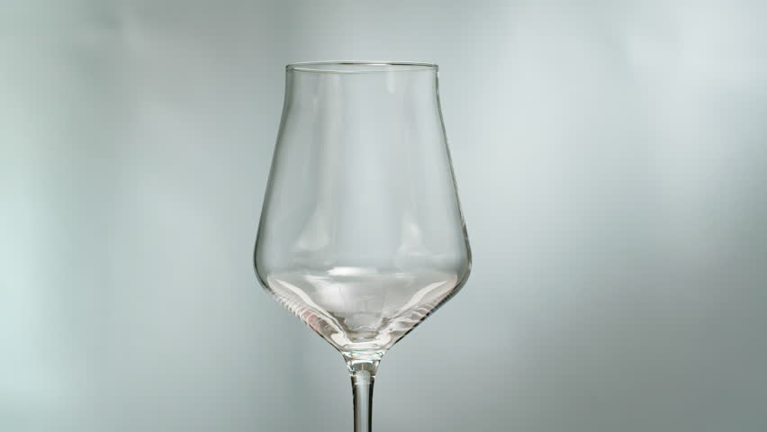 Orange or white wine bottle and glass against a sunset in a peaceful vineyard, pouring of ecological natural wine. 