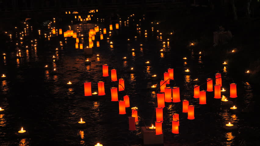 Red and orange paper Japanese lanterns on the water late at night in the dark
