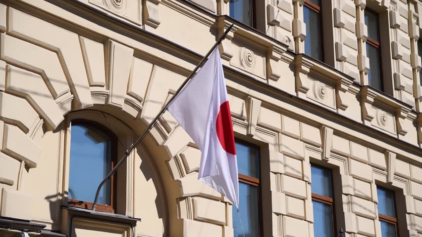 Close-up view of Japanese national flag located on building wall and swaying on the wind in a sunny summer day. Real time video. Soft focus. National symbols theme.