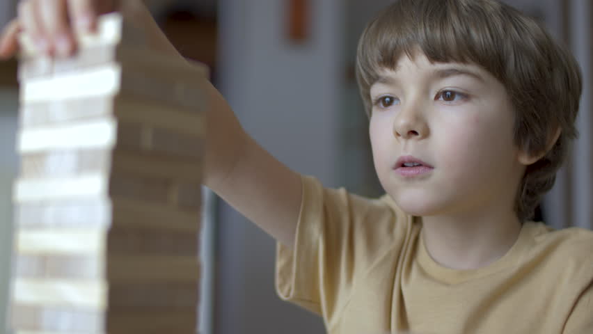 Child Having Fun Building Constructor Tower of Wooden Blocks. Boy Playing Wooden Block Tower Game at Home. Board Creative Game. Child Development Education Leisure. Play With Wooden Building Blocks.