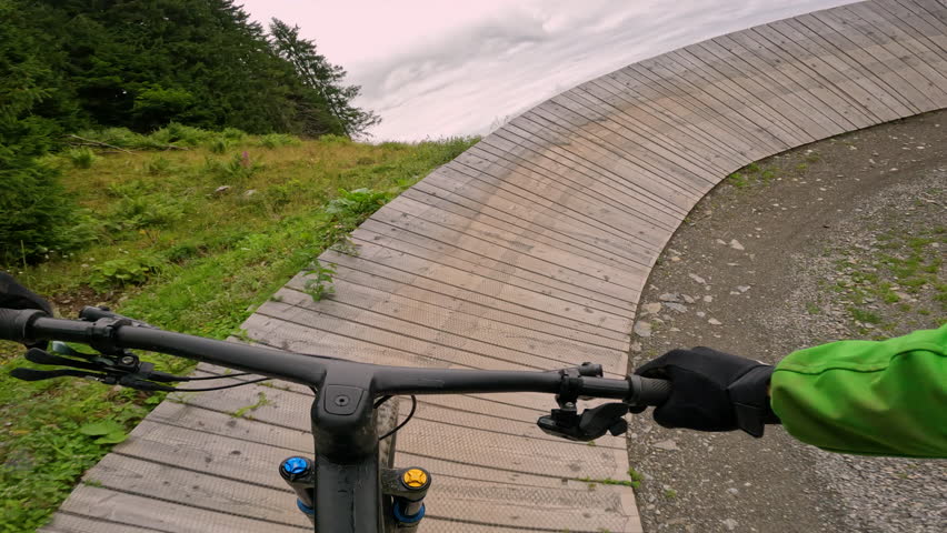 POV: Thrilling helmet cam shot of riding a mountain bike down a scenic downhill trail in rural Slovenia. Racing down a steep hill on a mountain bike during a fun day at the bike park. Fast bike ride.