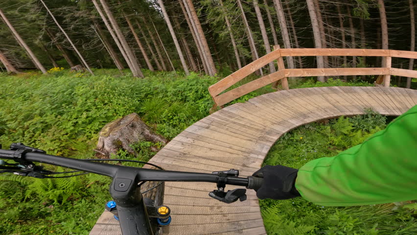 POV: Riding a mountain bike down a wooden plank part of a fast downhill trail in the scenic countryside. Adrenaline filled helmet cam shot of riding a mountain bike down a trail in rural Slovenia.