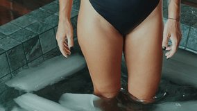 Sportive Woman with Beautiful Body Steps in Cold Water of Swimming Pool with Ice Cubes. Healthy Person in Bathtub Full of Chilled Liquid for Youth Therapy. Winter Routine in Large Bath for Good Health - Powered by Shutterstock - Get 15% off with code: PIKWIZARD15