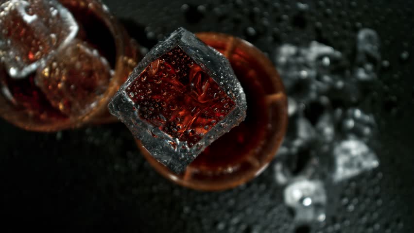 Super Slow Motion Shot of Ice Falling into Fresh Cola Lemonade Followed by Camera at 1000fps.