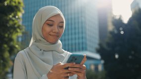 Muslim Woman Texting With Her Husband and Receives Pleasant Messages on Her Phone. Beautiful, Positive Islamic Girl Lively Chats With Friends and Smiles at Her Phone Screen. People and Technology - Powered by Shutterstock - Get 15% off with code: PIKWIZARD15