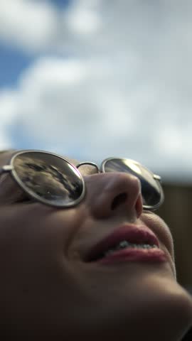 Vertical Screen: Portrait of a Laughing Beautiful Young Woman Looking Up at the Sky in Round Fashionable Sunglasses