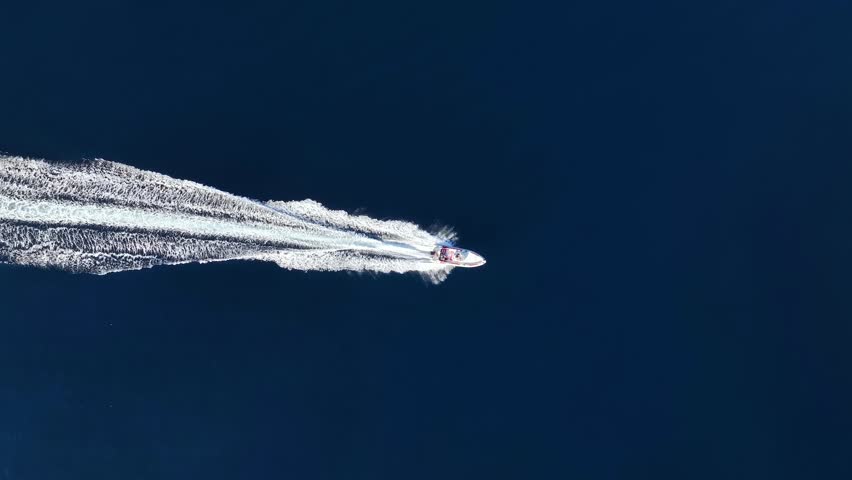 High aerial overhead view of a RIB Boat crossing the blue ocean with speed
