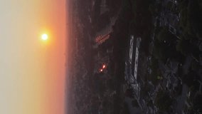 An aerial, vertical video of the Southern State Parkway on Long Island, NY. Shot after sunrise with some traffic in the distance. The camera is high up and stationary by the parkway, facing the sun. - Powered by Shutterstock - Get 15% off with code: PIKWIZARD15