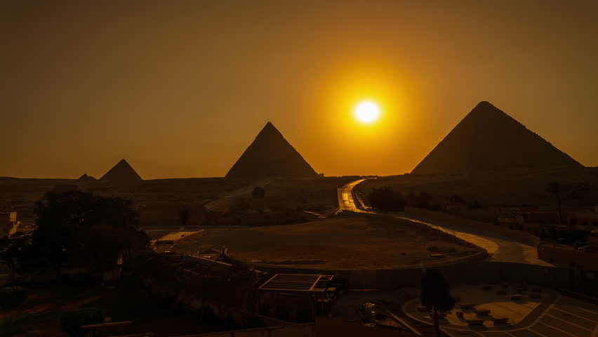The sun is setting behind the three pyramids (Khafre, Khufu and Menkaure) in Giza close to Cairo in Egypt