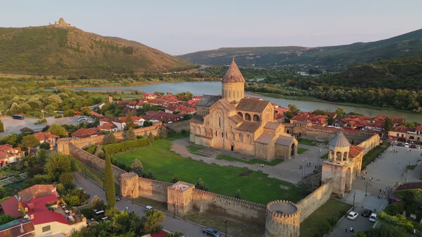 Aerial around view of great Svetitskhoveli Cathedral in Mtskheta, Georgia. Old Svetitskhoveli Church in center of Mtskheta village - UNESCO World Heritage. Jvari monastery on the mountain