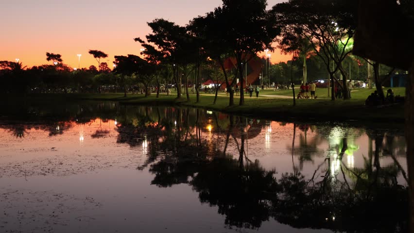 Lake reflecting the colors of the sky after sunset and people walking on a hiking trail next to the lake