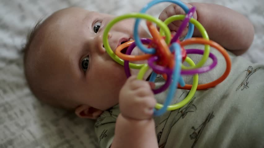 Baby Caucasian boy playing with a colorful toy on a white play mat