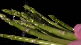 A cinematic macro shot of green and fresh asparagus under running water. Black background - Powered by Shutterstock - Get 15% off with code: PIKWIZARD15