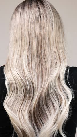 Vertical video of unrecognizable model with long blond curly hair in slow motion