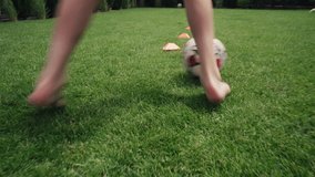 Knee level shot of athletic boy dribbling soccer ball through orange disc cones training outside in house courtyard on grass lawn. Young football player prepares for competition. Hobby and sports. - Powered by Shutterstock - Get 15% off with code: PIKWIZARD15