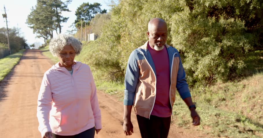 Lifestyle videos outdoor of people doing activities, walking outdoors on dirt road, elderly couple enjoying morning exercise together. a couple of people walking and conversing with each other