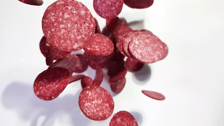 Flying salami slices. Pieces of smoked salami sausage on white background. Fresh cured sausage for a sandwich, pepperoni for pizza