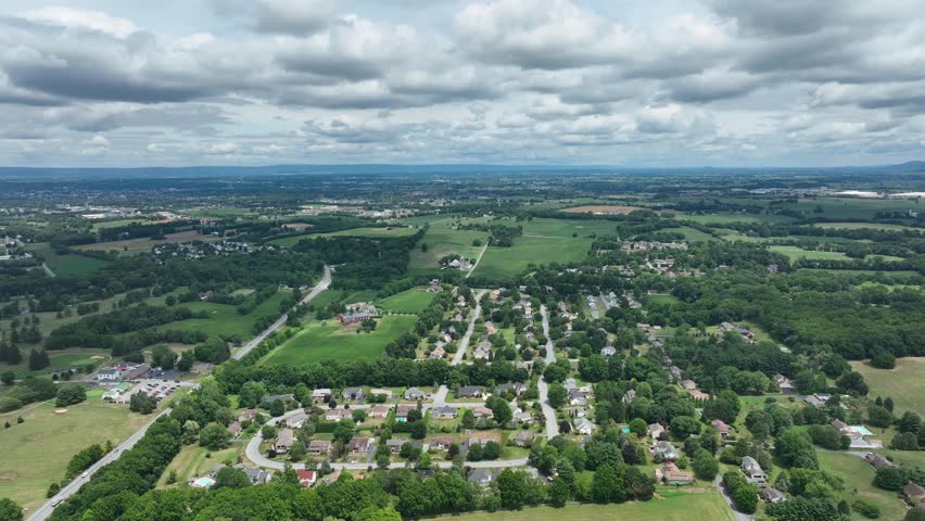 Suburban neighborhood with rows of houses and green lawns in America. Green suburb landscape of America. Small village in USA. Aerial trucking wide shot.