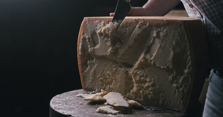 Super slow motion macro of artisan cheesemaker controls quality of parmesan cheese during ripening process at production creamery dairy factory at 1000 fps.