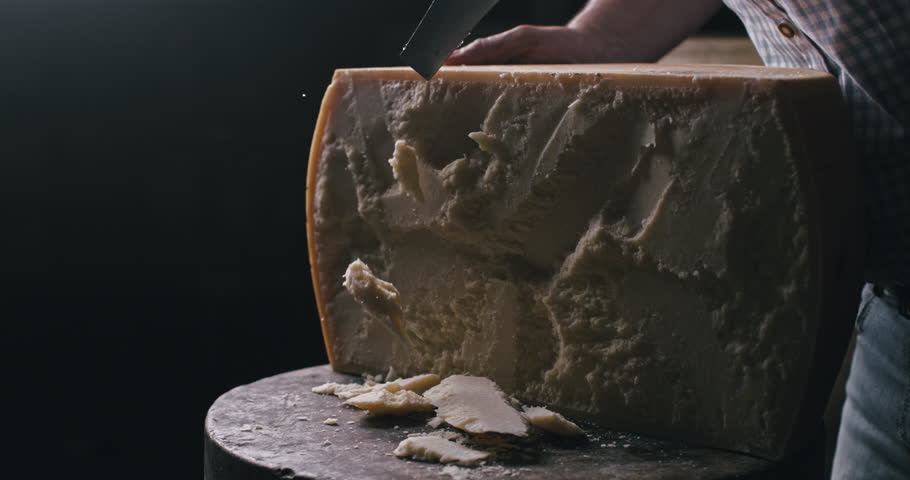 Super slow motion macro of artisan cheesemaker controls quality of parmesan cheese during ripening process at production creamery dairy factory at 1000 fps.
