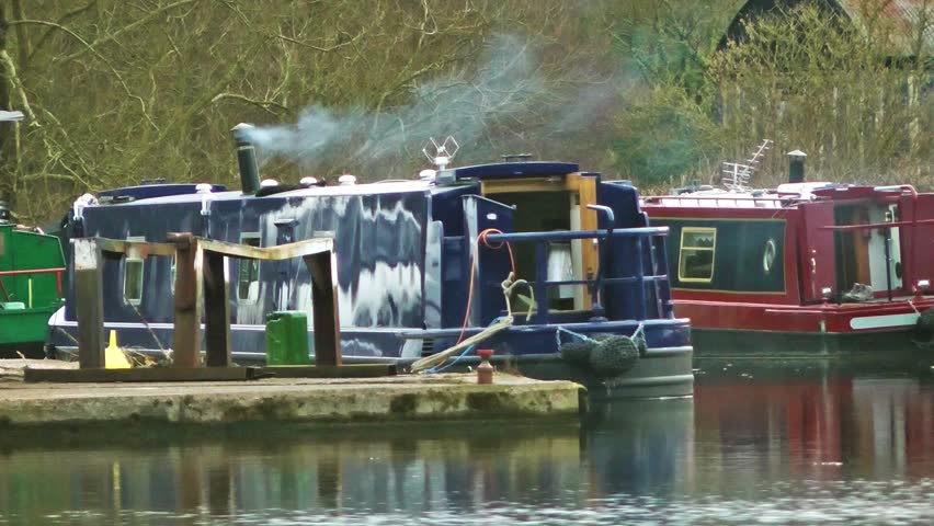 Narrow Boat on a mooring with wood smoke slowly rising from it's chimney -
