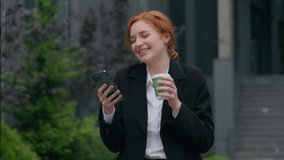 Joyful laughing young Caucasian ginger businesswoman girl female executive woman client hands using mobile phone networking online typing message surfing internet drinking coffee outside city downtown - Powered by Shutterstock - Get 15% off with code: PIKWIZARD15