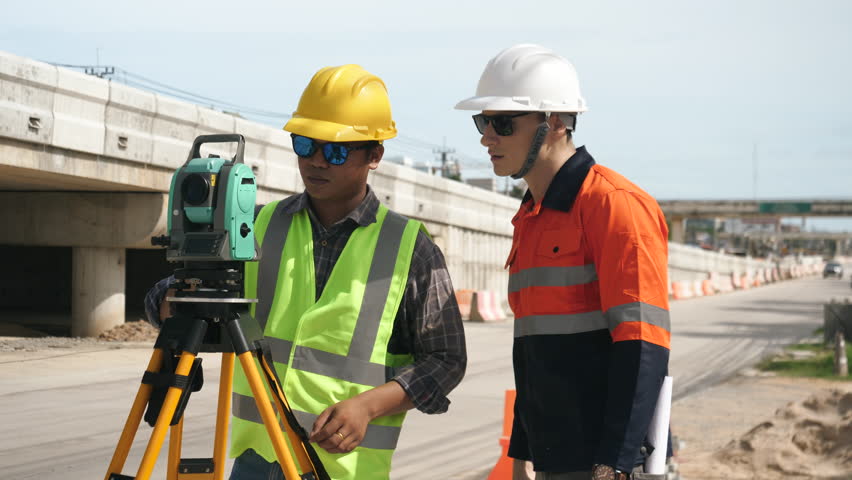 Civil engineers or surveyors talking to architect at road construction site, teamwork. Surveying with modern tools.