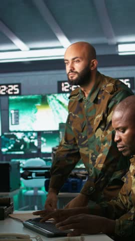 Vertical video Army telecommunications operators using radio and satellite gear, inputting data on systems. Military dispatchers managing communications networks, typing on keyboard, camera B