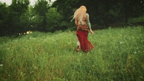 young happy fantasy blonde woman queen runs walks in green summer nature flowering field forest trees. Candid girl princess Back rear view fluttering skirt red boho dress waving, slow motion video 4k. - Powered by Shutterstock - Get 15% off with code: PIKWIZARD15