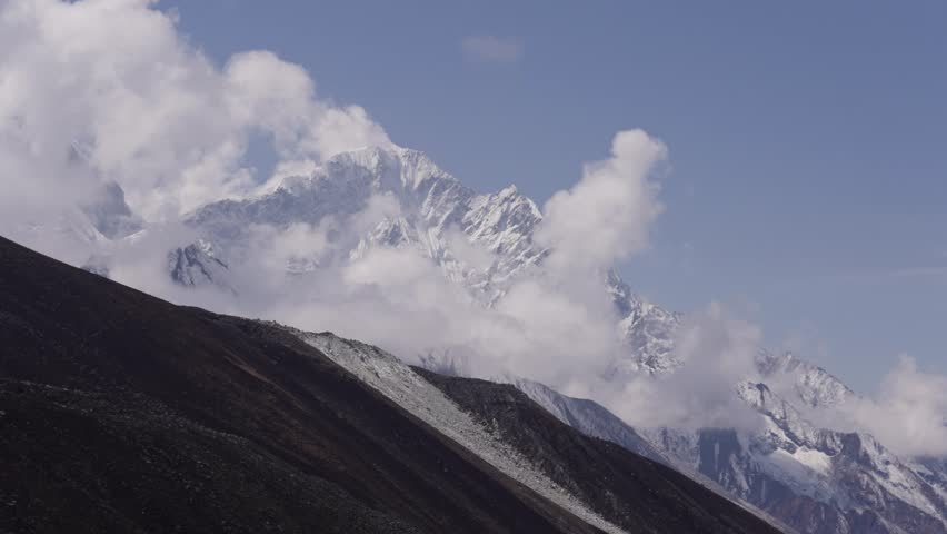 Time lapse shot of moving clouds around snowy mount Everest in Nepal. Sunny day with blue sky in Asia. Wide shot.