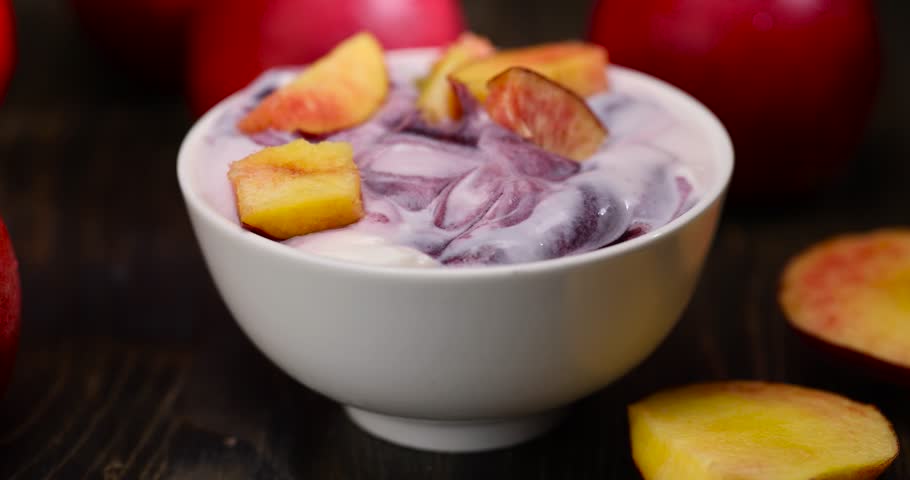 fresh yogurt with jam and pieces of ripe nectarine, natural yogurt in a white bowl with fruits
