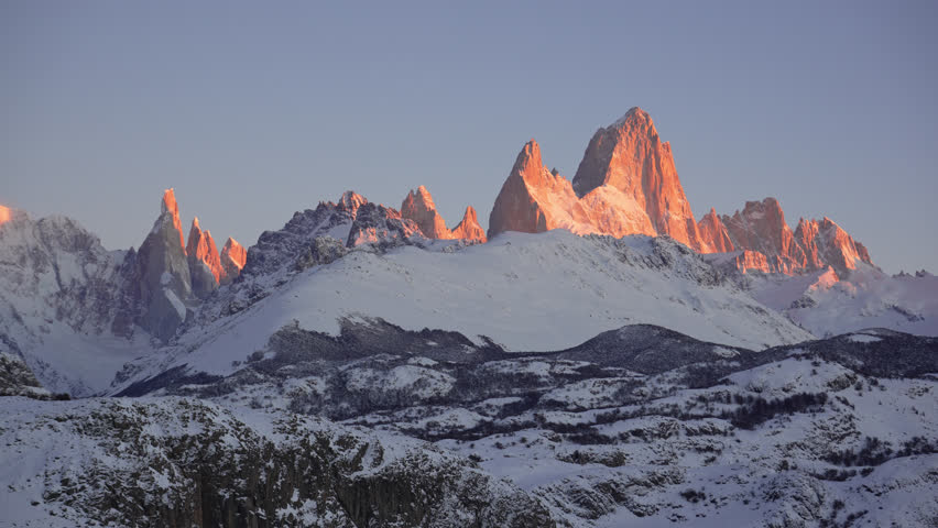 Mount Fitz Roy and Cerro Torre peaks in the early morning with vibrant orange light in Patagonia, Argentina. Static zoomed-in view