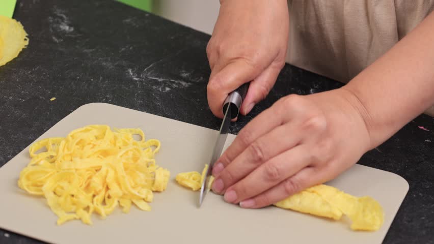 Female Hand Slicing Telur Rawis, Thin Slice Egg Omelete for Nasi Kuning or Nasi Uduk Side Dish Topping 
