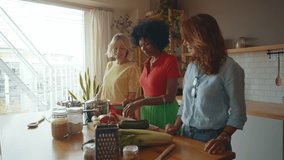 Cinematic image of a group of senior women cooking and having fun at home. Reunion and social gathering of three female friends in a beautiful kitchen. - Powered by Shutterstock - Get 15% off with code: PIKWIZARD15