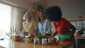 Cinematic image of a group of senior women cooking and having fun at home. Reunion and social gathering of three female friends in a beautiful kitchen. - Powered by Shutterstock - Get 15% off with code: PIKWIZARD15