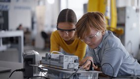 Two classmates working togeter on circuit board, building robot in after-school robotics club. Children learning robotics in Elementary school. - Powered by Shutterstock - Get 15% off with code: PIKWIZARD15