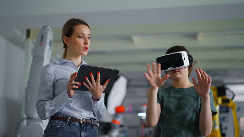 Video of schoolgril with VR headset on head and teacher with tablet. Children learning robotics in Elementary school, using modern technology, virtual reality. - Powered by Shutterstock - Get 15% off with code: PIKWIZARD15