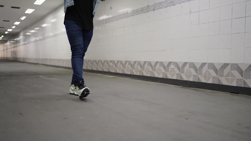 Confidence African man in stylish clothing walking in city street crossing tunnel at night. Handsome black people in denim jacket and jeans enjoy urban outdoor lifestyle and nightlife.