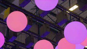 Close up view of LED orb-shaped lights hanging from the ceiling, moving up and down, and changing color - Powered by Shutterstock - Get 15% off with code: PIKWIZARD15
