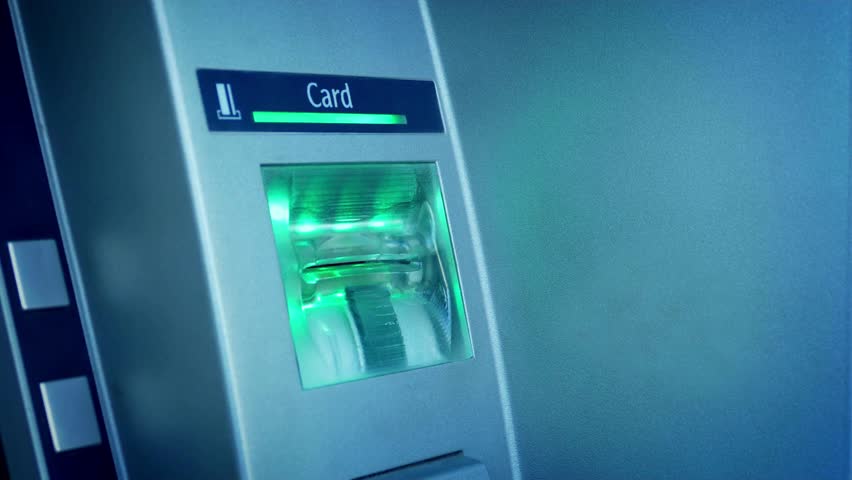 Close-up view of hand inserting a credit card into an ATM teller machine cash withdrawing money