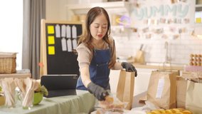 Portrait of Young Asian woman bakery shop owner preparing customer order bakery in delivery paper bag on kitchen counter. Small business e-commerce online catering food and drink entrepreneur concept. - Powered by Shutterstock - Get 15% off with code: PIKWIZARD15