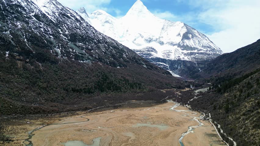 Drone shot of the scenic and breathtaking Yading nature reserve luorong pasture with Mount Yangmaiyong in background, located in Garze Tibetan Autonomous Prefecture, Sichuan