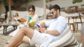 4K Businessman remote working online business chatting on smartphone at beach cafe. Caucasian man relax and enjoy outdoor lifestyle travel nature at tropical island ocean on summer holiday vacation. - Powered by Shutterstock - Get 15% off with code: PIKWIZARD15