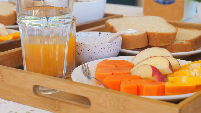 Breakfast tray with fresh fruits, slices of bread, glass of orange juice, and yogurt, arranged on wooden tray, creating healthy and nutritious meal setting. Healthy Eating and Lifestyle.