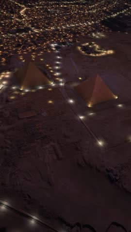 3D - Aerial top view of the Pyramids of Giza at dusk in Egypt. The city and the pyramids illuminated