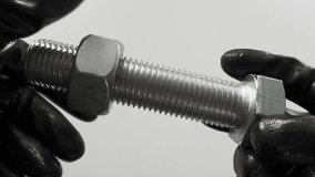 Thread control, a bolt in the hands of black gloves. Checking the quality of the threaded thread with a nut of the appropriate size. - Powered by Shutterstock - Get 15% off with code: PIKWIZARD15