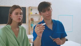 Two young students draw math problems on the glass with a marker and look at them intently, trying to find a solution to the problem. - Powered by Shutterstock - Get 15% off with code: PIKWIZARD15