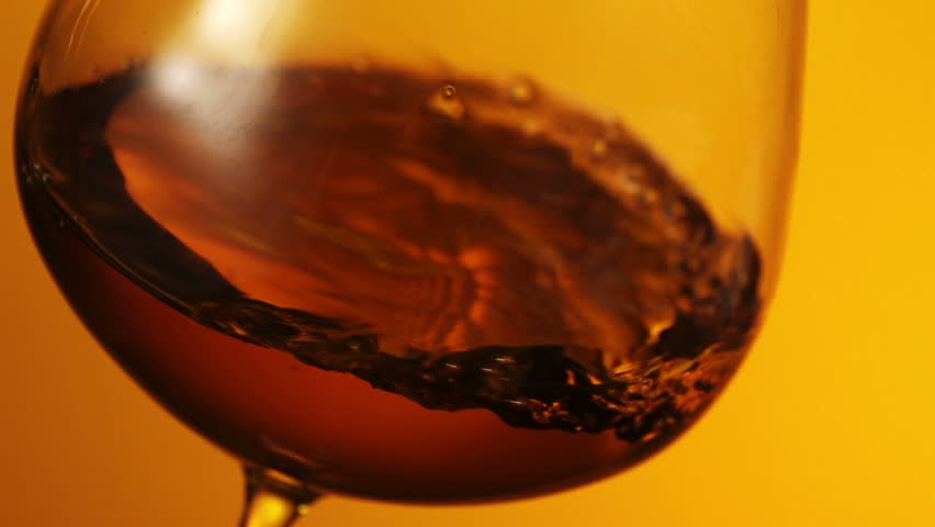 The glass with splashes cognac on black background
