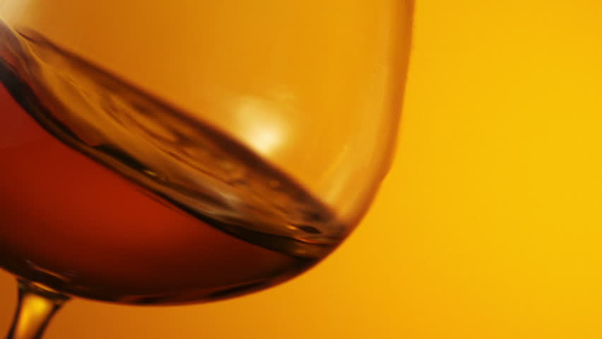 The glass with splashes cognac on black background